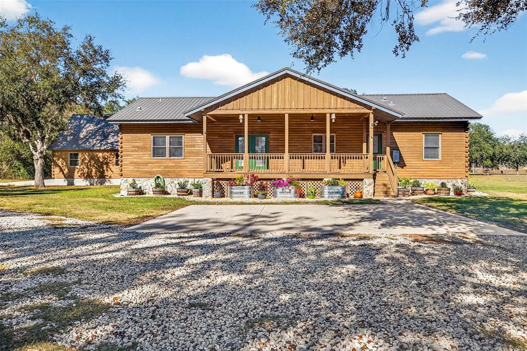 A single-story wooden house with a covered front porch and a gravel driveway — 6750 SUTTON OAKS LANE, ZEPHYRHILLS, FL