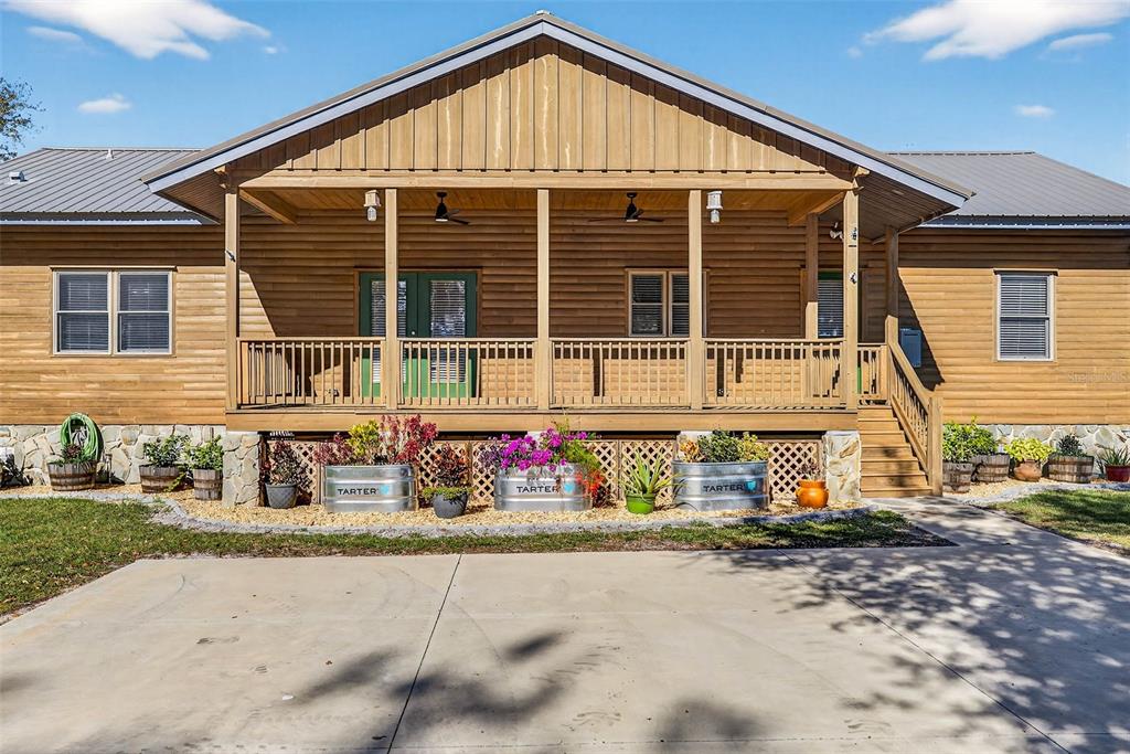 A wooden house features a front porch, metal roof, and metal planter boxes — 6750 SUTTON OAKS LANE, ZEPHYRHILLS, FL