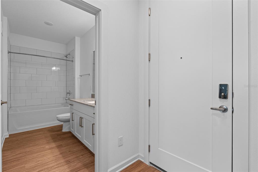 A view of a bathroom with a tub-shower combo next to a white entry door — 1700 RANCH ROAD UNIT A1-7305, NOKOMIS, FL