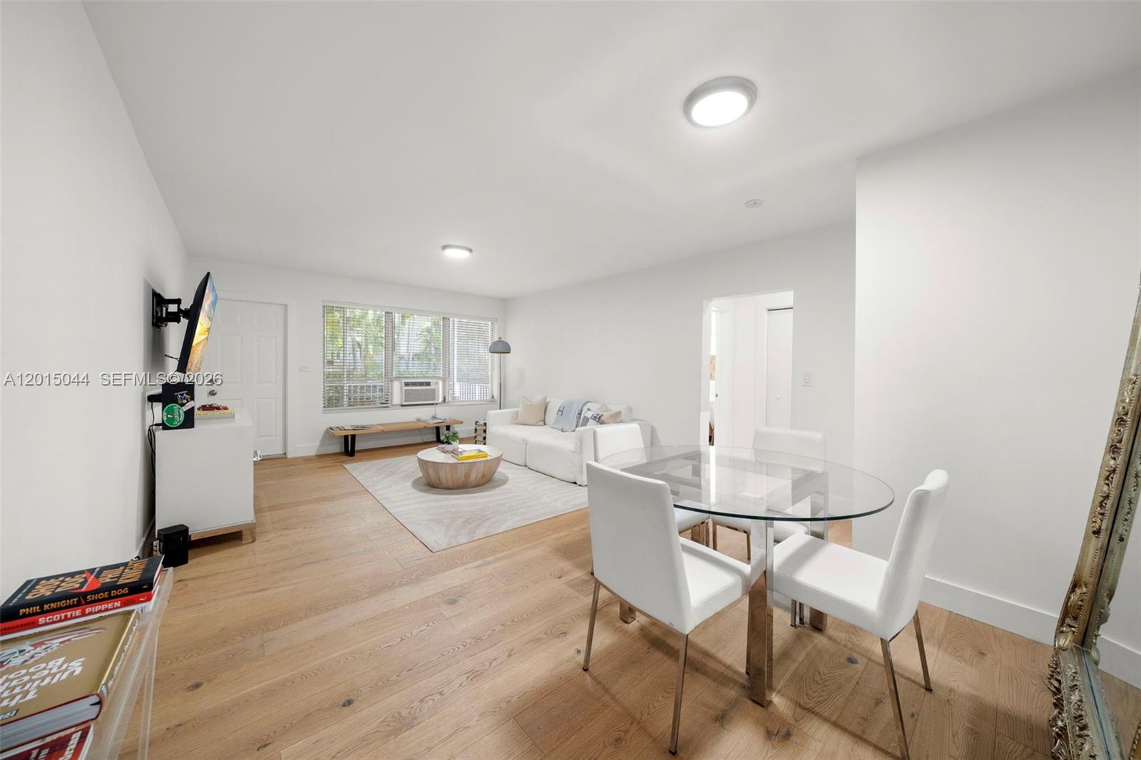 A bright living and dining area features light wood floors and a glass dining table — 1125 99th St # 9, Bay Harbor Islands FL 33154, BAY HARBOR ISLANDS, FL