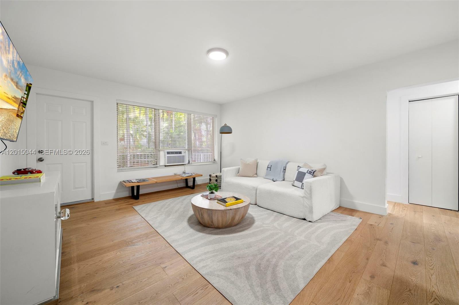 A living room features a white sofa, a round wooden coffee table, and hardwood floors — 1125 99th St # 9, Bay Harbor Islands FL 33154, BAY HARBOR ISLANDS, FL