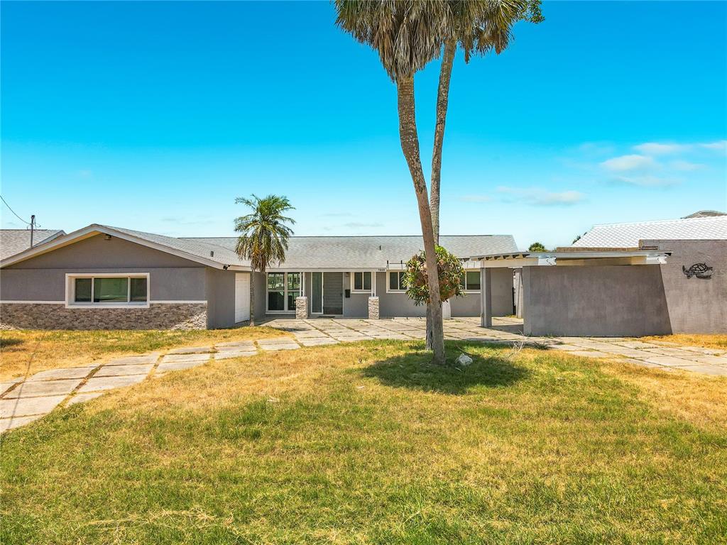 A single-story house with a gray exterior, stone accents, and a paved front courtyard — 7905 11TH AVENUE S, ST PETERSBURG, FL