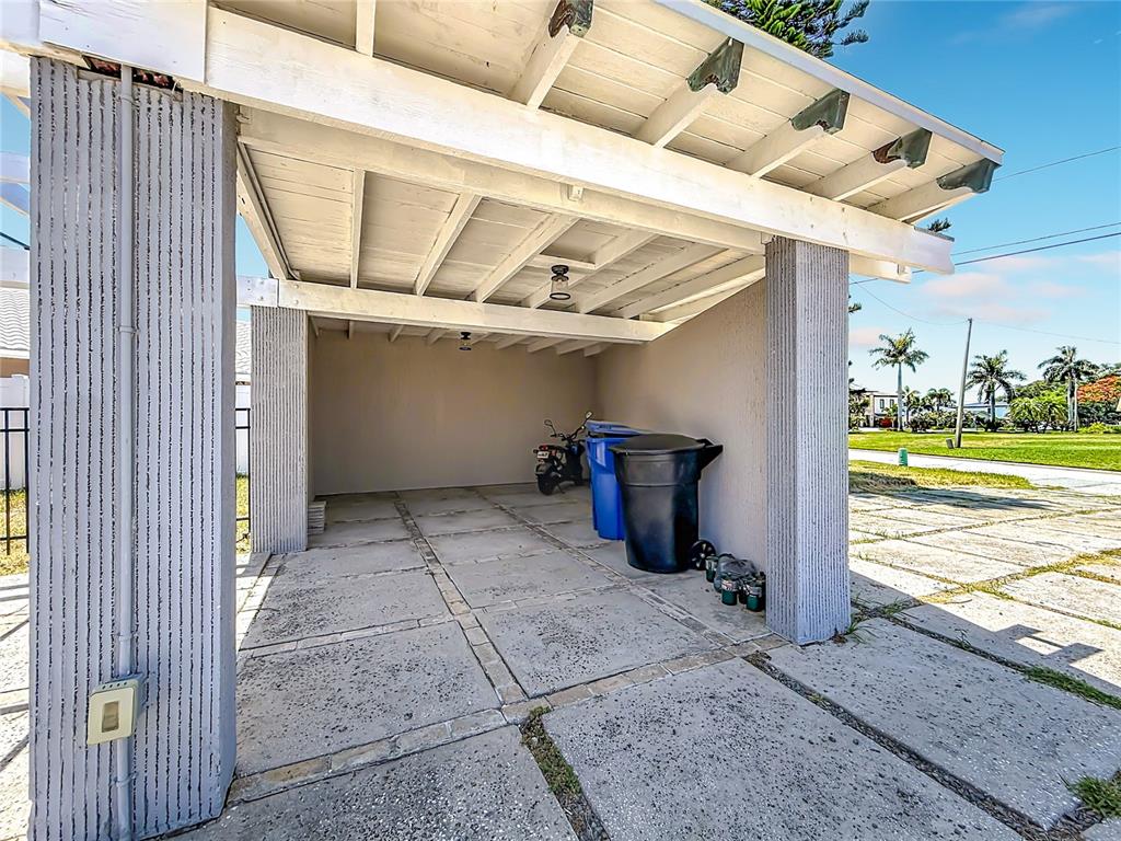 A covered carport with concrete flooring, two support pillars, and a white wooden ceiling — 7905 11TH AVENUE S, ST PETERSBURG, FL