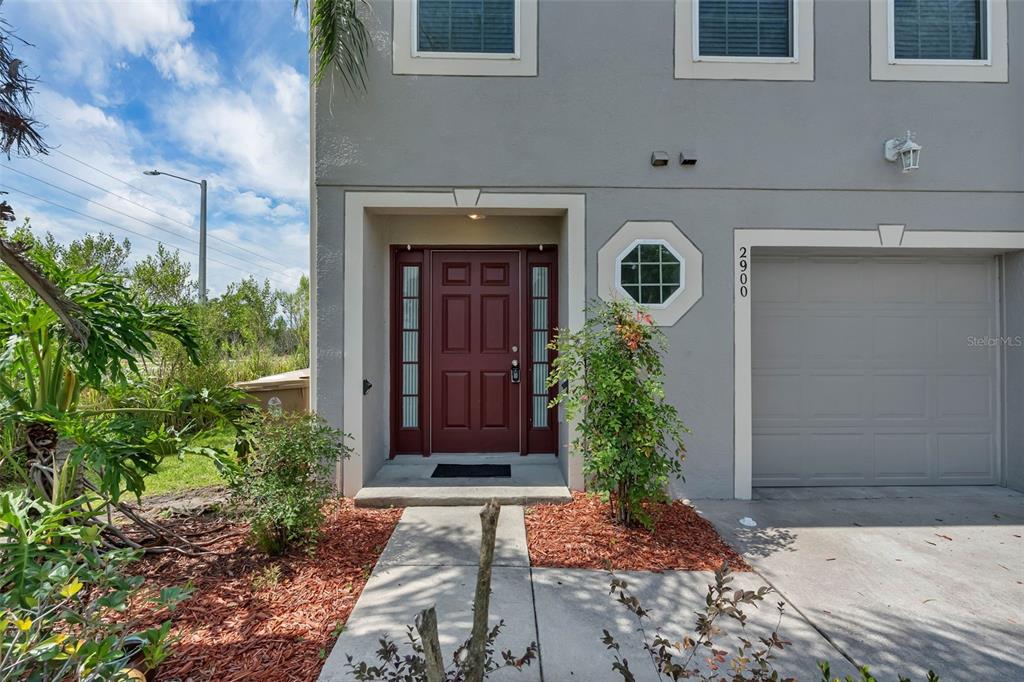 The exterior of a two-story gray townhouse features a red front door and garage — 2900 CLARABELLE COURT, KISSIMMEE, FL