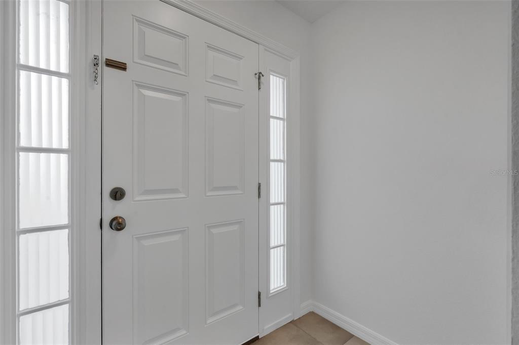 A white front door with side windows and a tiled floor in an entryway — 2900 CLARABELLE COURT, KISSIMMEE, FL