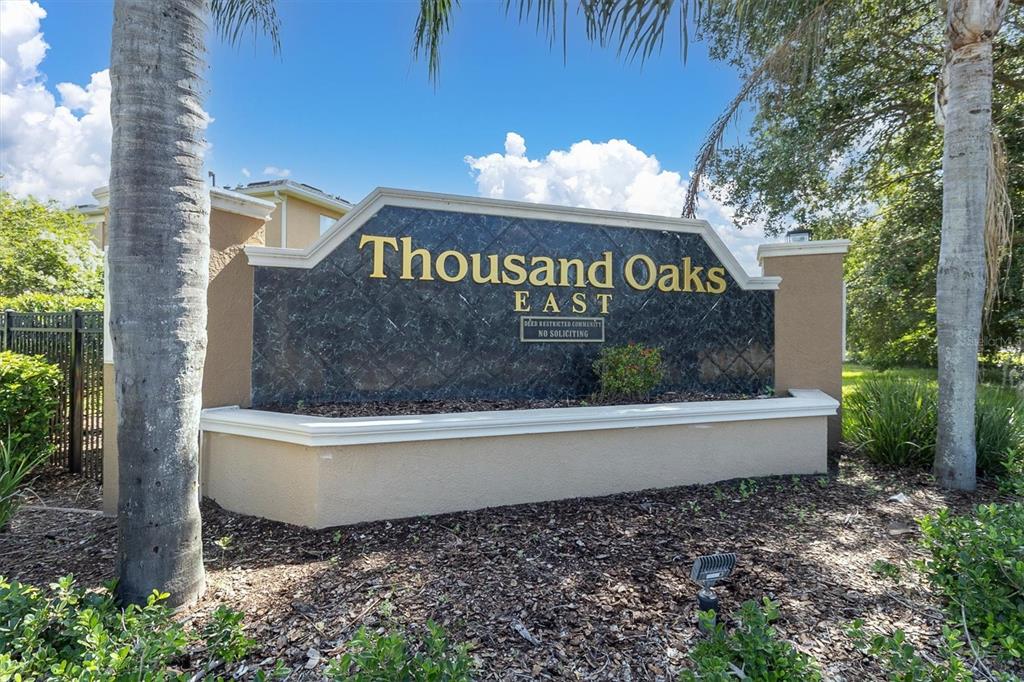 A two-story townhouse exterior features a covered porch, beige stucco walls, and a concrete walkway — 9782 TRUMPET VINE LOOP, TRINITY, FL