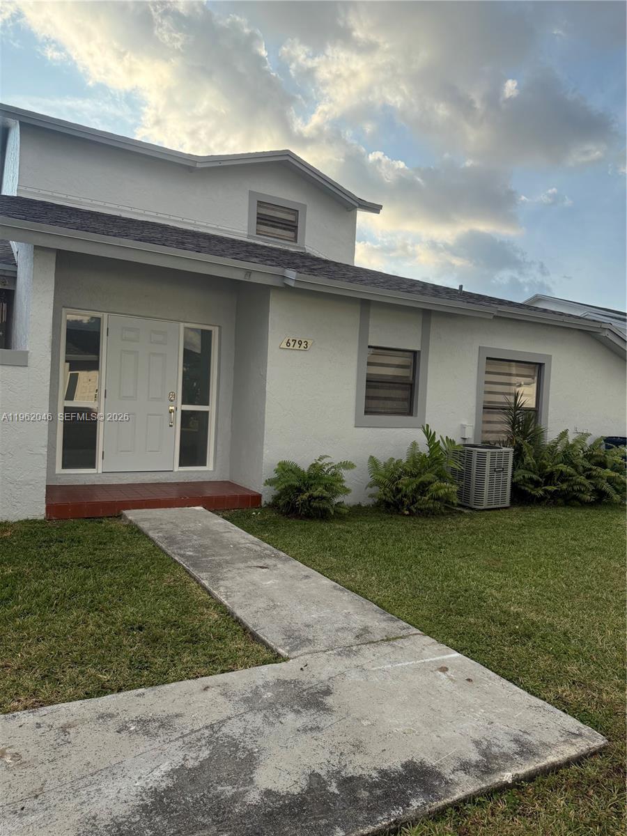 A white house exterior features a front door, a concrete walkway, and landscaped bushes — 6793 SW 152nd Pl # 93, Miami FL 33193, MIAMI, FL