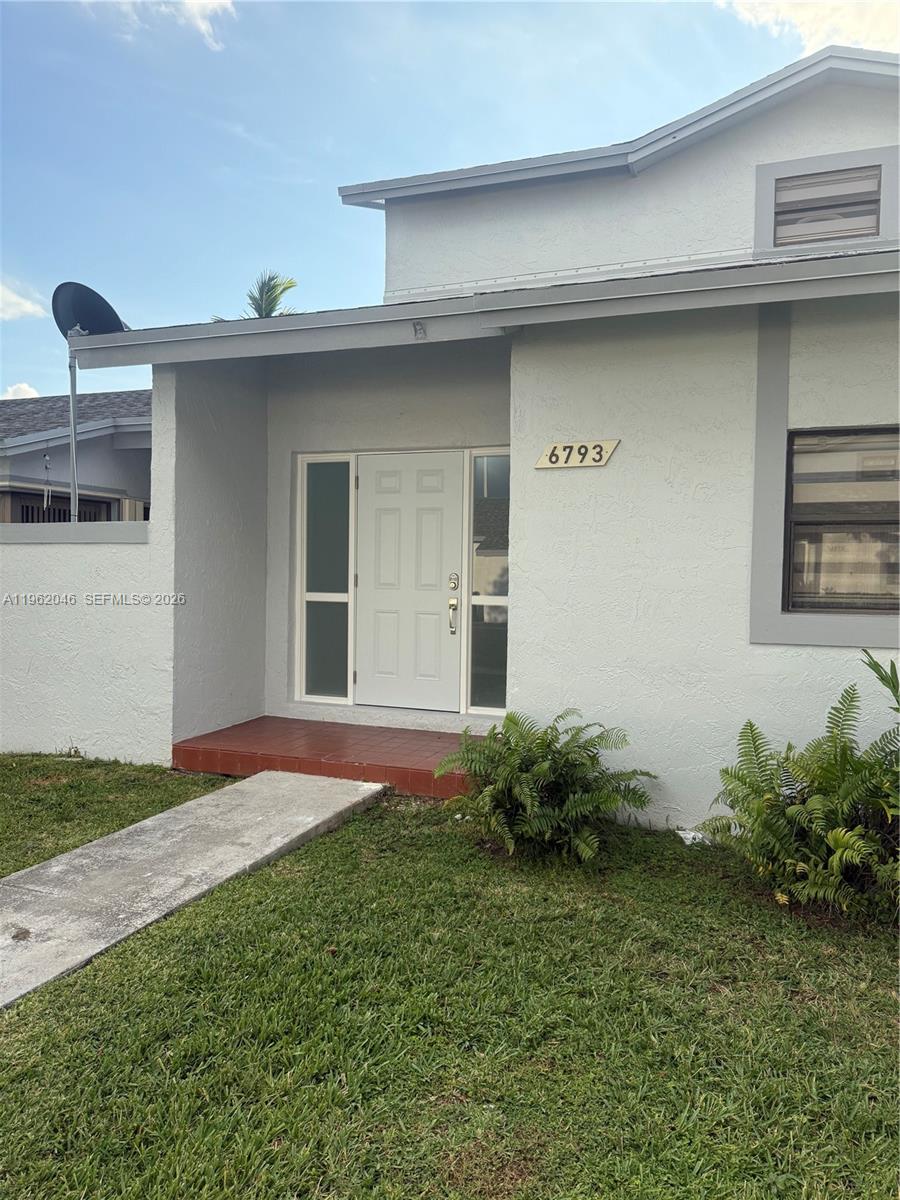 The exterior of a white house features a front door with sidelights and a walkway — 6793 SW 152nd Pl # 93, Miami FL 33193, MIAMI, FL