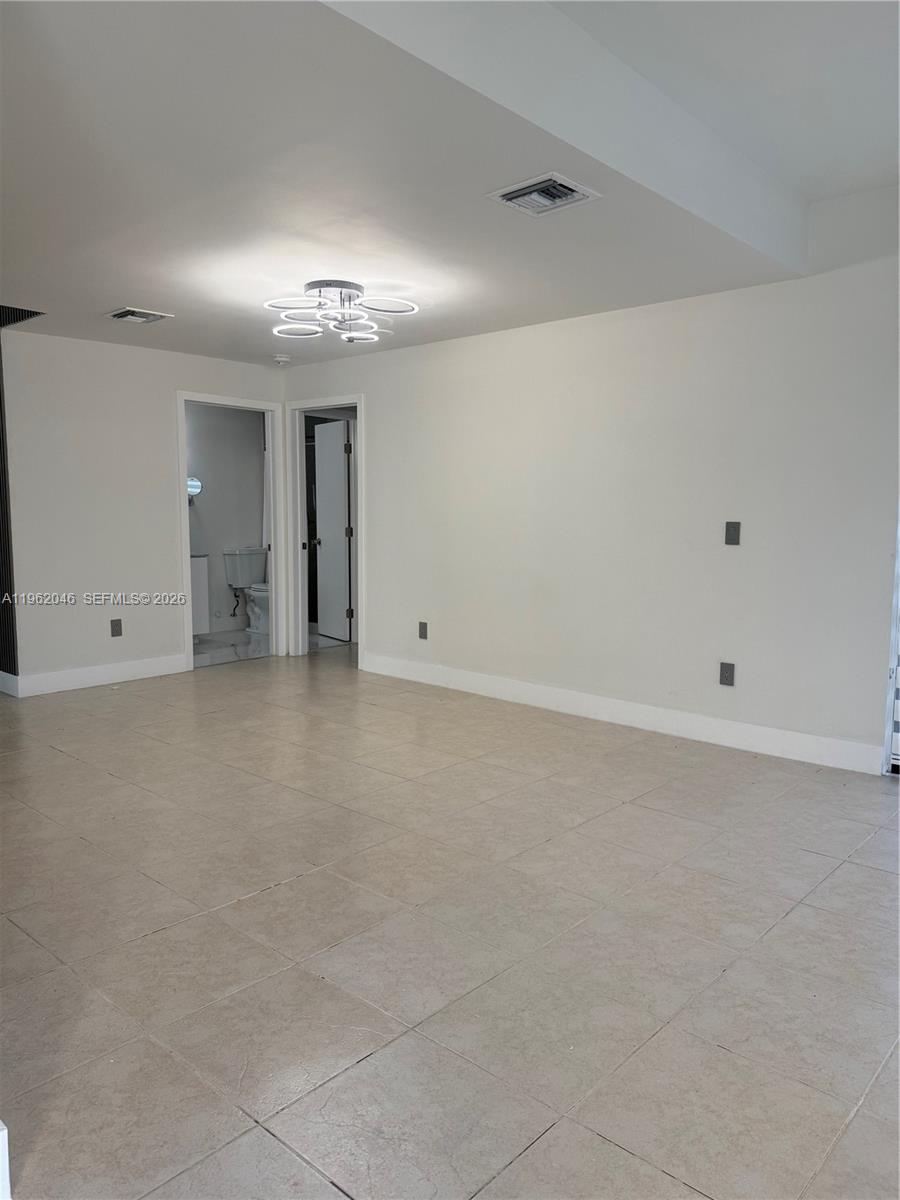 An empty room features light-colored tile flooring, white walls, and a modern circular ceiling light — 6793 SW 152nd Pl # 93, Miami FL 33193, MIAMI, FL