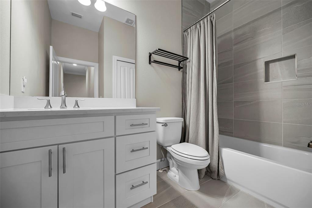 A bathroom features a white vanity, a toilet, and a tiled shower with a curtain — 726 GRAND CYPRESS LANE, TARPON SPRINGS, FL