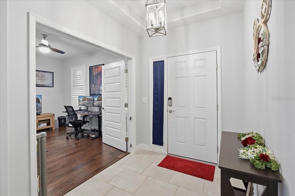 An entryway with tile flooring leads to a home office with dark wood floors — 8721 BAYVIEW CROSSING DRIVE, WINTER GARDEN, FL