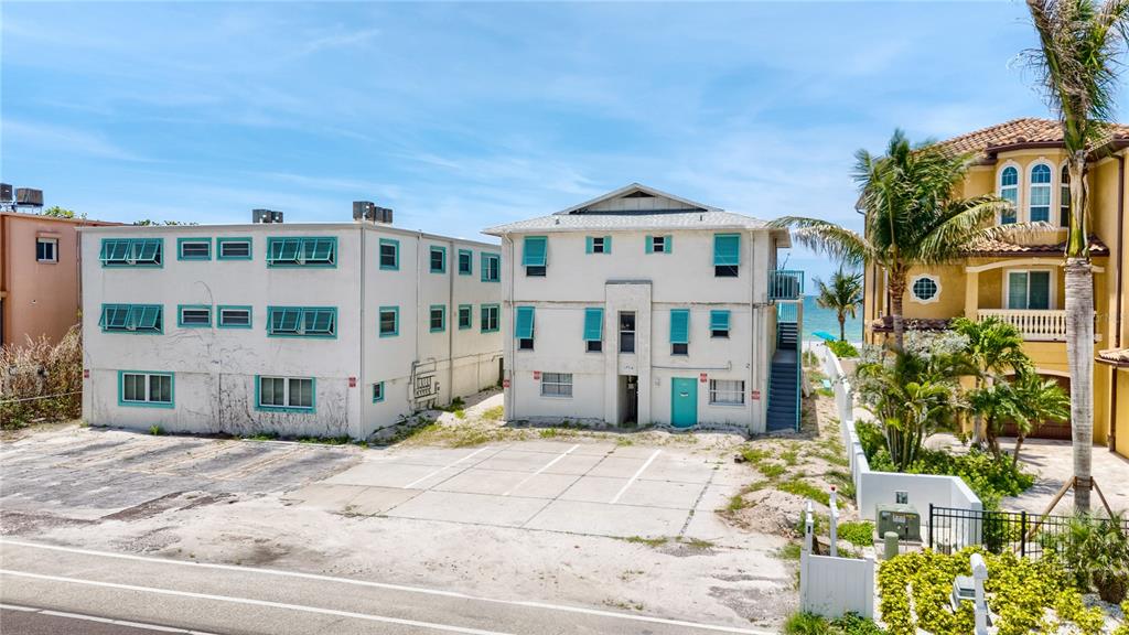 An exterior view of two multi-story apartment buildings with teal shutters near a beach — 19310 GULF BOULEVARD, INDIAN SHORES, FL