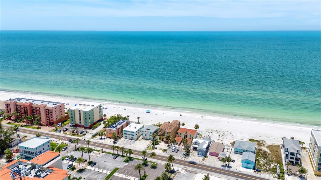 An aerial view shows a beach with multi-story buildings and a road along the coast — 19310 GULF BOULEVARD, INDIAN SHORES, FL