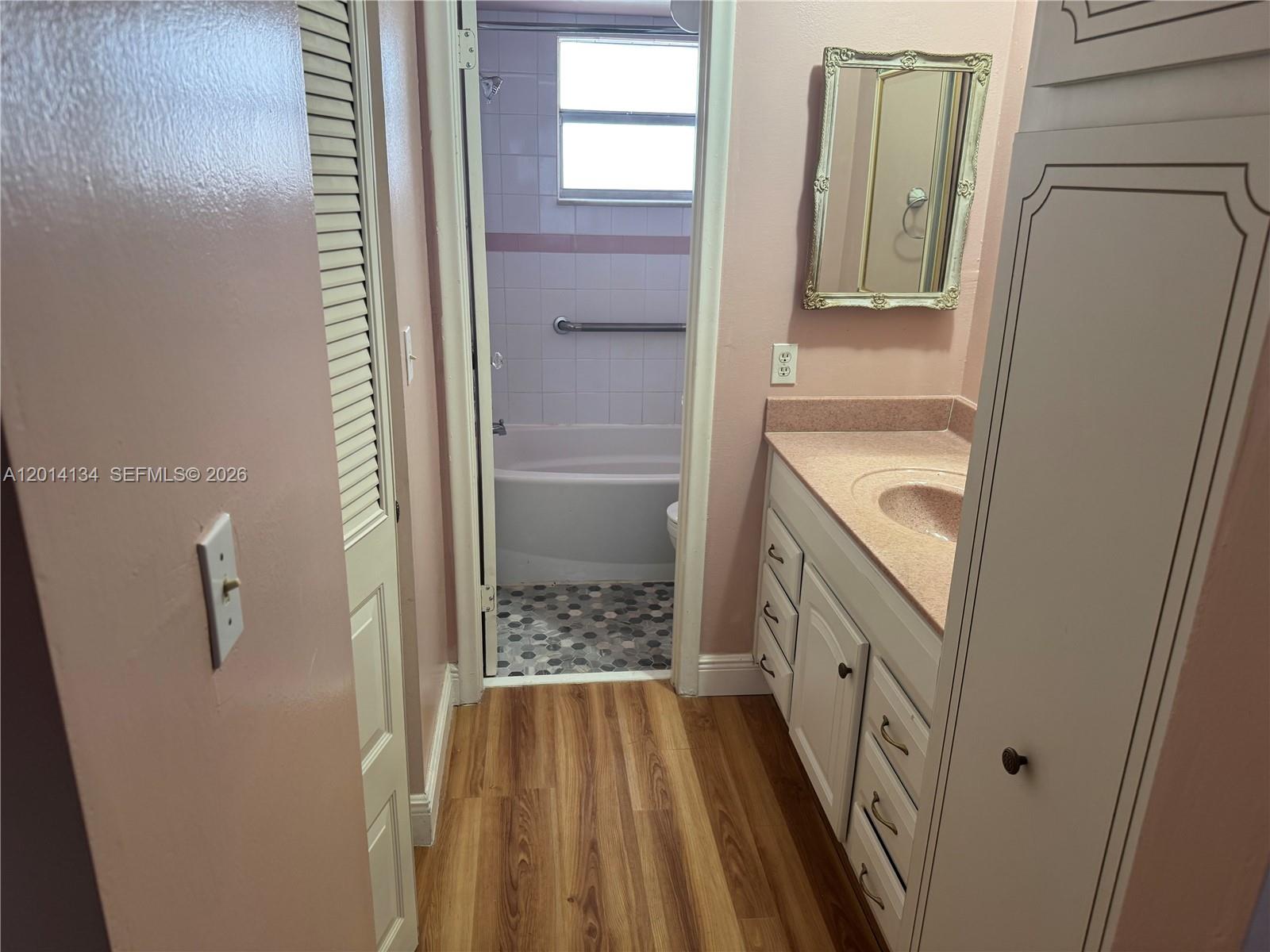 A bathroom features a pink vanity, wood-look flooring, and a separate tub and shower area — 3774 Inverrary Blvd # 106P, Lauderhill FL 33319, LAUDERHILL, FL