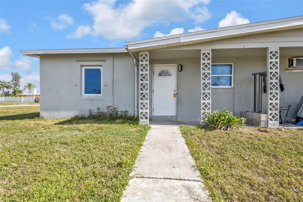 The exterior of a single-story house features a white front door and decorative concrete columns — 21242 COULTON AVENUE, PORT CHARLOTTE, FL