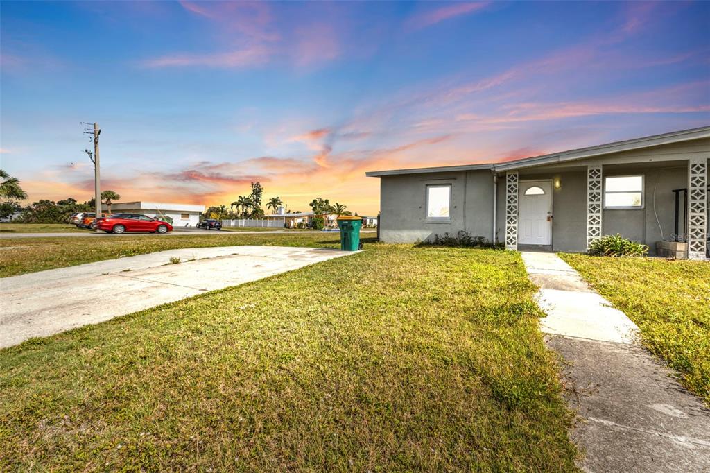 A single-story house exterior features a concrete driveway, a front walkway, and decorative lattice columns — 21242 COULTON AVENUE, PORT CHARLOTTE, FL