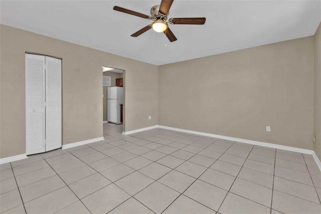 A room with beige walls, large light-colored floor tiles, a ceiling fan, and a closet — 21242 COULTON AVENUE, PORT CHARLOTTE, FL