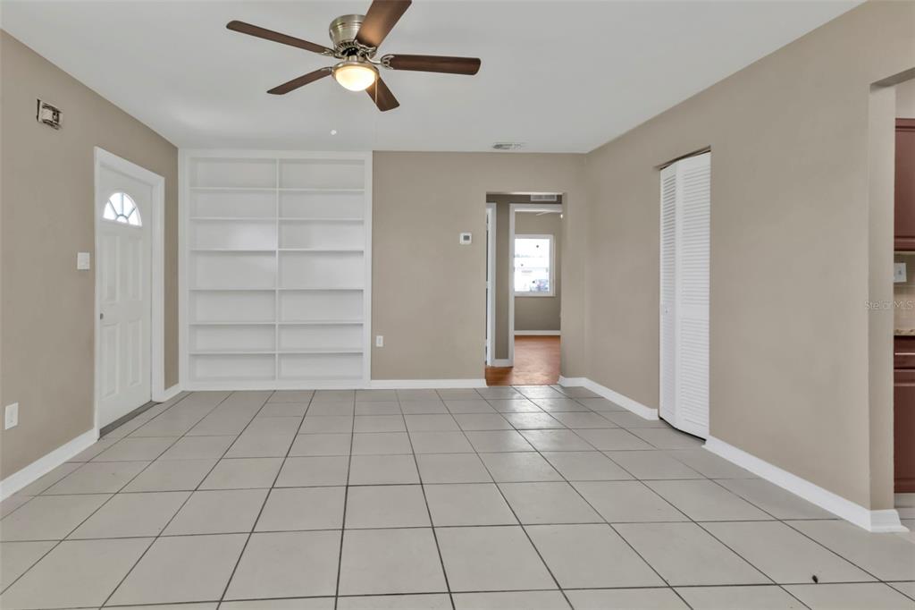 A room with light-colored tile flooring, a ceiling fan, built-in white shelving, and a doorway — 21242 COULTON AVENUE, PORT CHARLOTTE, FL