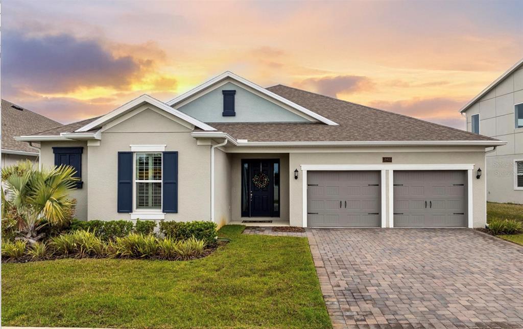 A single-story house with a two-car garage, light stucco exterior, and blue shutters — 18405 MOWRY COURT, ORLANDO, FL