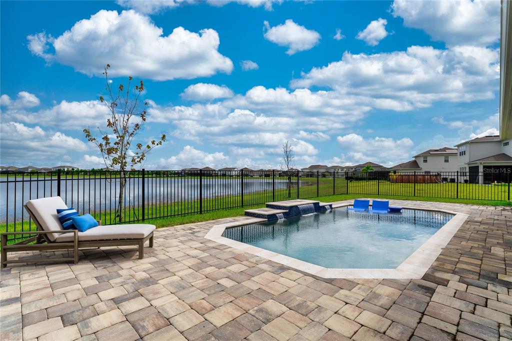 A backyard patio features a swimming pool with a water feature and a lounge chair — 18405 MOWRY COURT, ORLANDO, FL