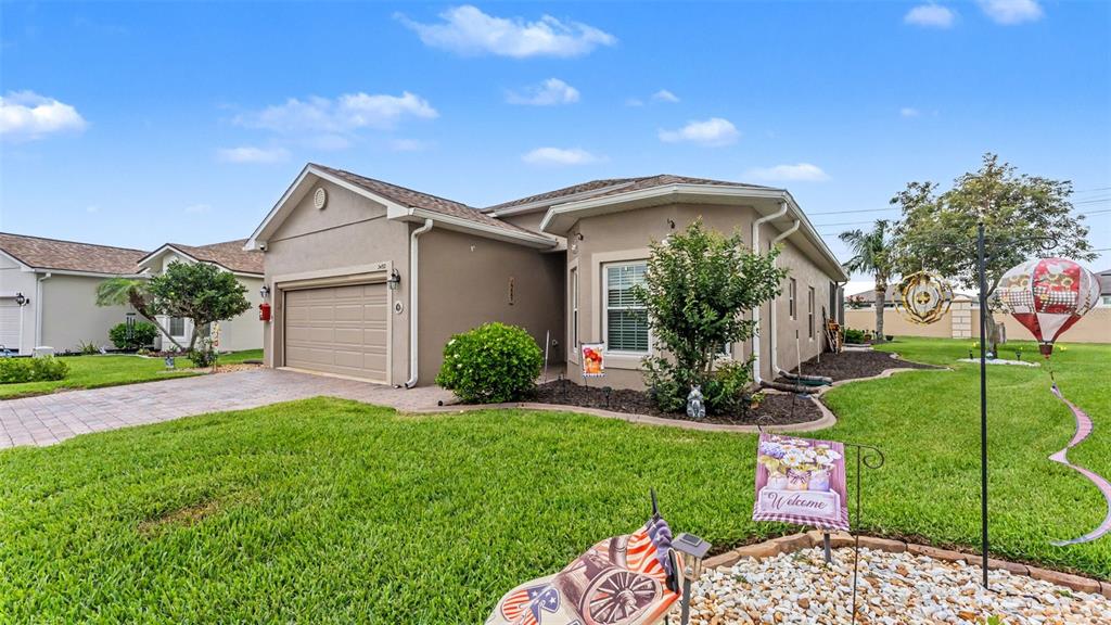 A single-story house with a tan stucco exterior, a two-car garage, and a landscaped lawn — 2452 SALZBURG LOOP, WINTER HAVEN, FL