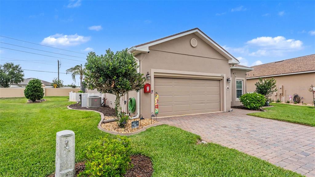 A beige single-story house with a two-car garage and a paved driveway — 2452 SALZBURG LOOP, WINTER HAVEN, FL