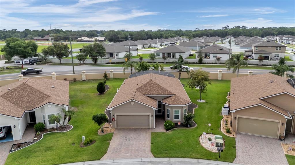 An aerial view shows three suburban houses with brown roofs and paved driveways — 2452 SALZBURG LOOP, WINTER HAVEN, FL