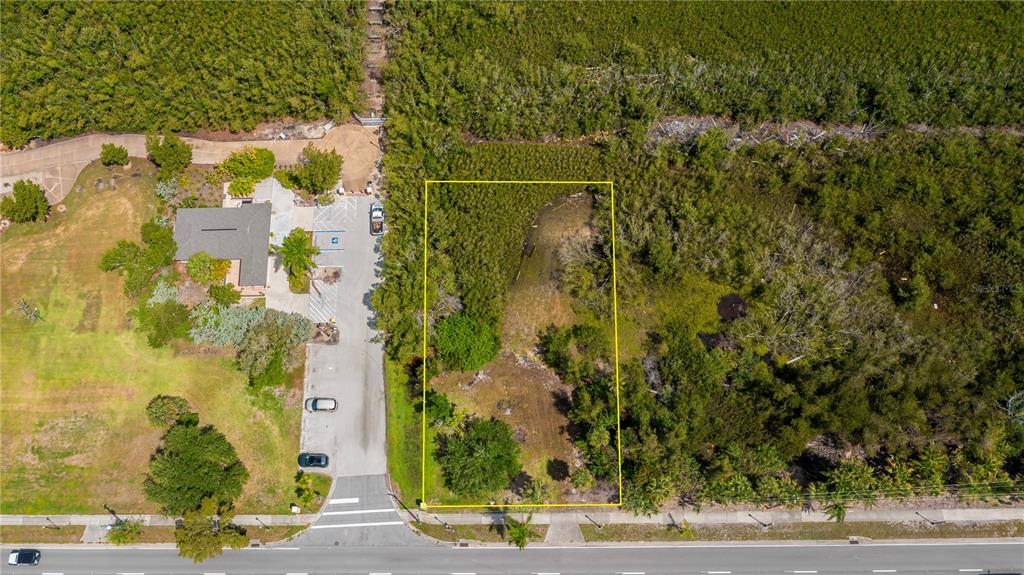 An aerial view shows a rectangular vacant lot outlined in yellow next to a parking area — 806 E MARION AVENUE, PUNTA GORDA, FL