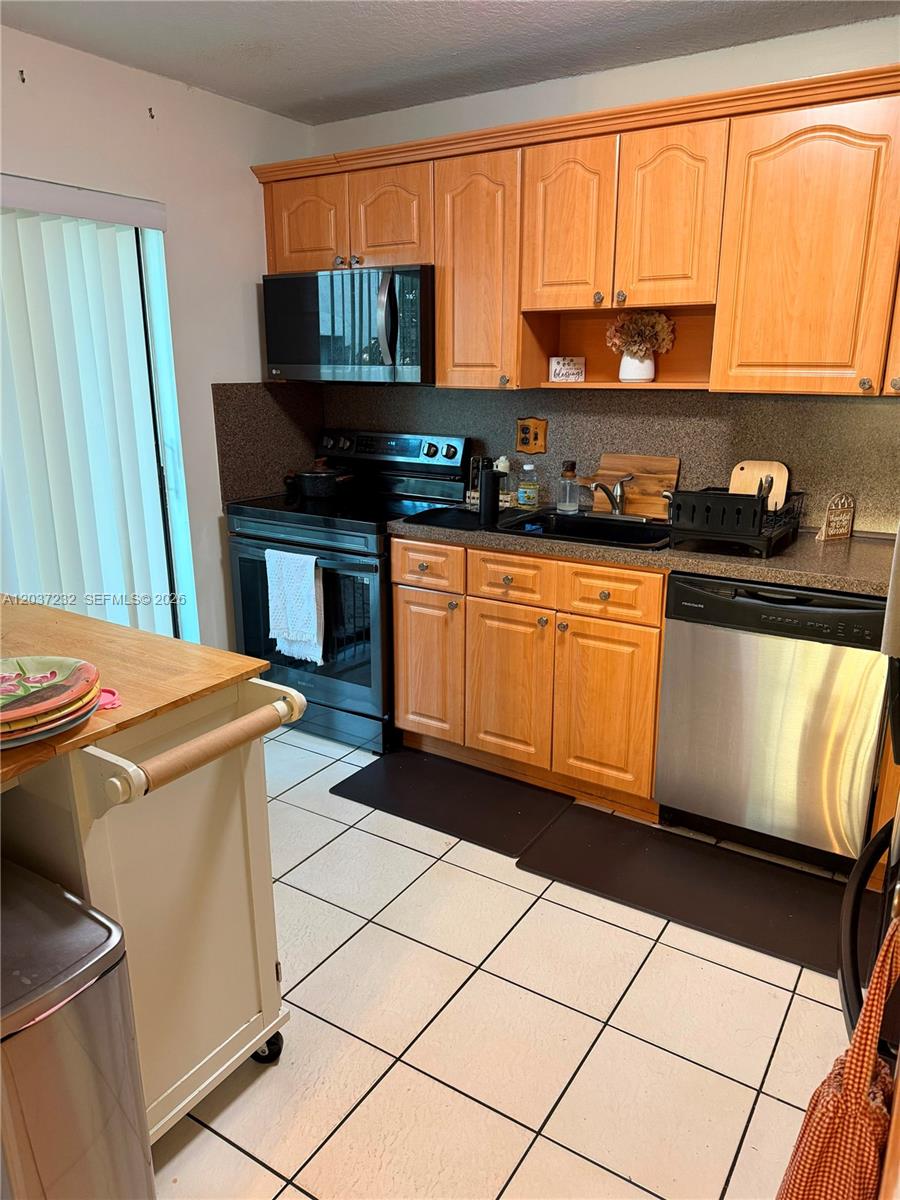A kitchen features wood cabinets, stainless steel appliances, a black sink, and tiled flooring — 10445 SW 154th Ct # 1, Miami FL 33196, MIAMI, FL