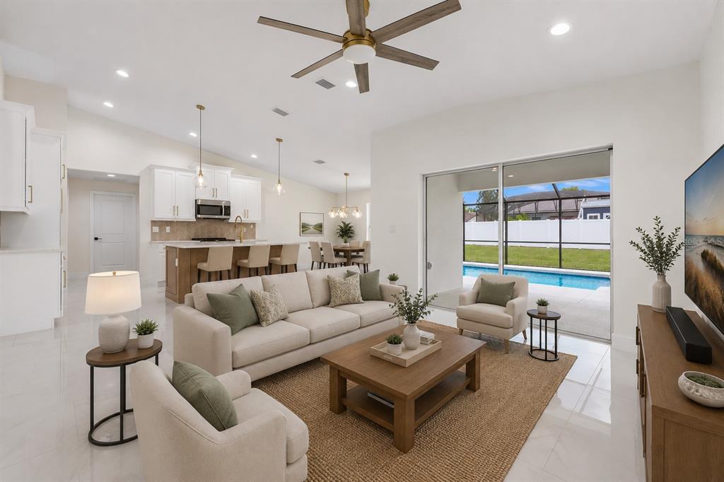 A bright open-concept living room and kitchen with white cabinetry, tile floors, and pool views — 32 FEDERAL LANE, PALM COAST, FL