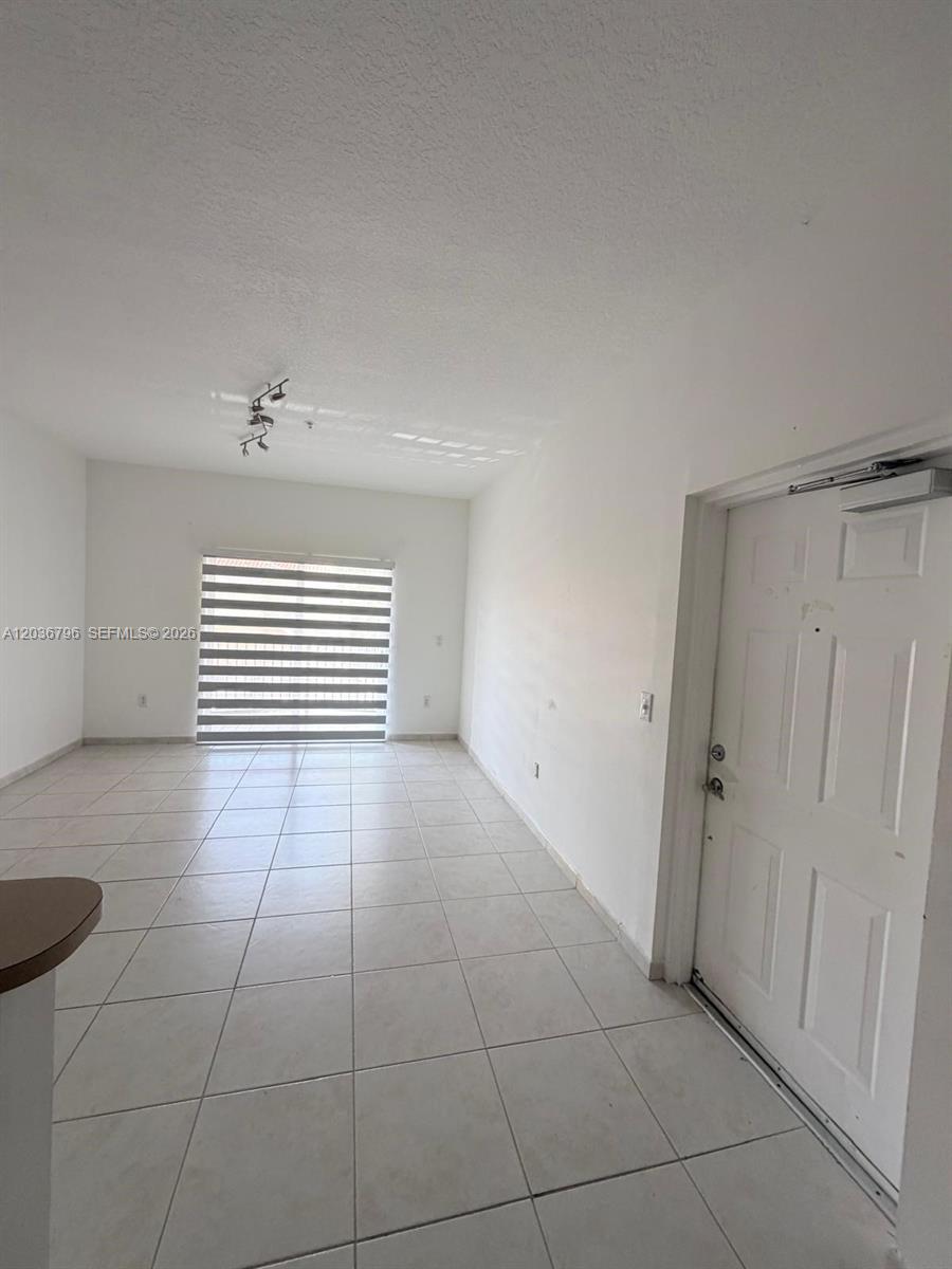 This room features white walls, light-colored floor tiles, a sliding glass door, and a door — 7220 NW 114th Ave # 20916, Doral FL 33178, DORAL, FL
