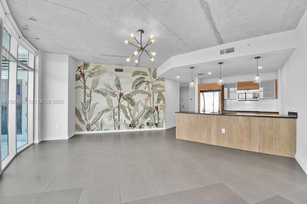An open-concept living area features a tropical wallpaper accent wall, concrete ceiling, and kitchen island — 3301 NE 1st Ave # H2509, Miami FL 33137, MIAMI, FL