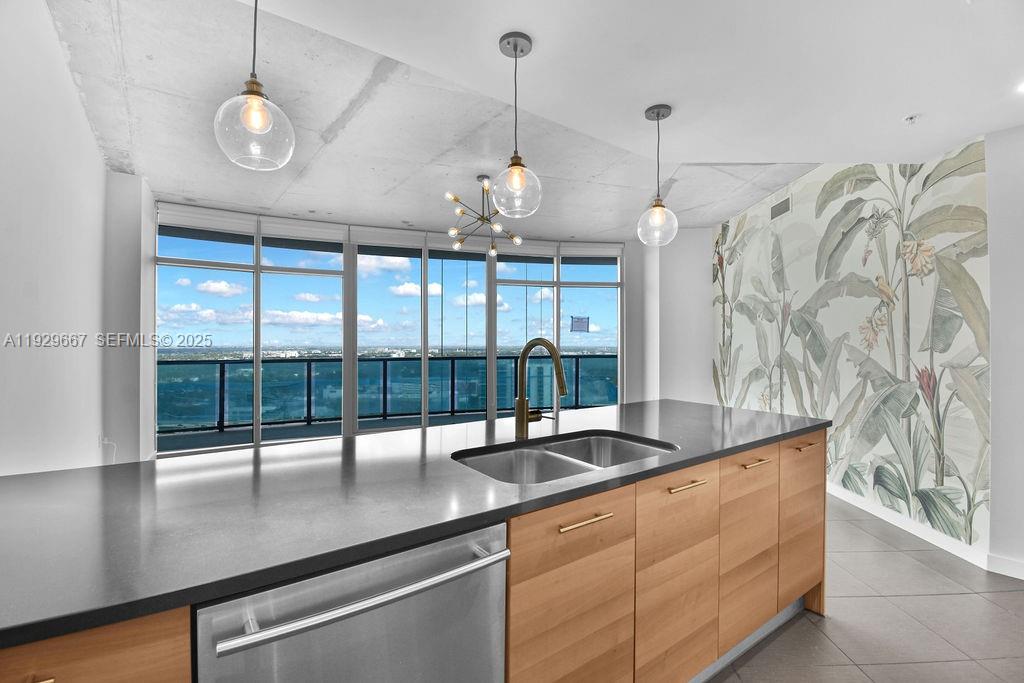 A kitchen island with a sink sits before floor-to-ceiling windows and a botanical wallpaper wall — 3301 NE 1st Ave # H2509, Miami FL 33137, MIAMI, FL