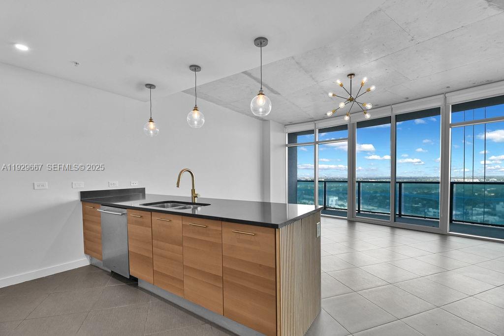 A modern kitchen features wood cabinets, a black countertop, and floor-to-ceiling windows with city views — 3301 NE 1st Ave # H2509, Miami FL 33137, MIAMI, FL