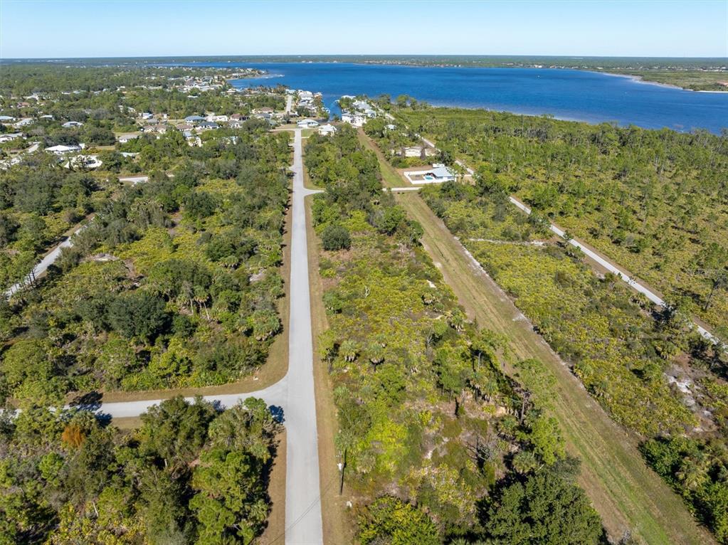 An aerial view shows a paved road extending through a wooded area toward a lake — 4388 SCHNEIDER STREET, PORT CHARLOTTE, FL