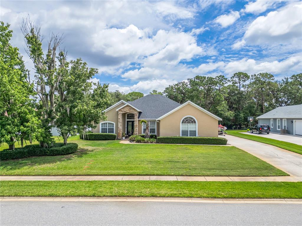 A single-story tan house with a stone entryway and a large front lawn — 2807 DEERFIELD STREET, ST CLOUD, FL