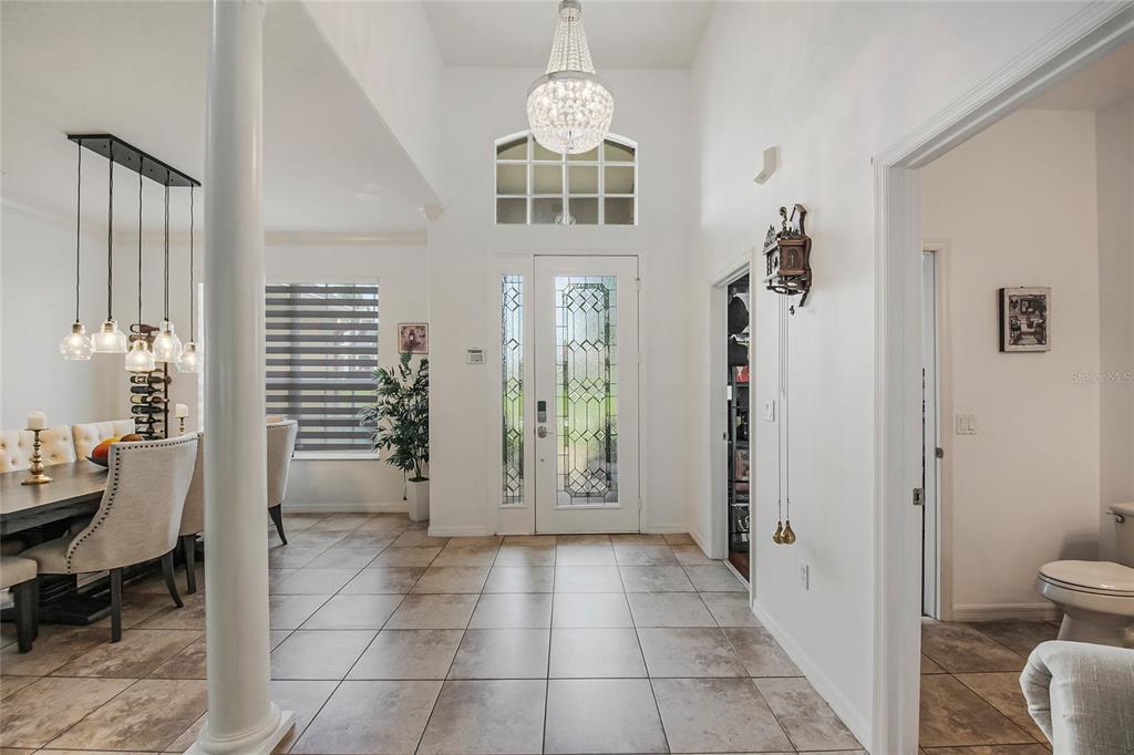 A bright entryway features tiled floors, a crystal chandelier, and a view into the dining room — 2807 DEERFIELD STREET, ST CLOUD, FL