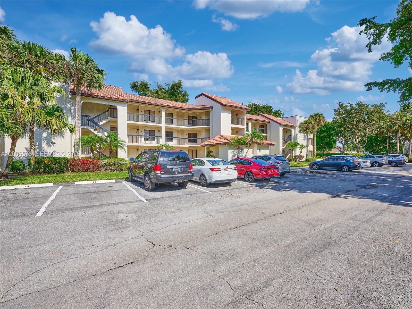 A three-story apartment building with a parking lot in the foreground — 10143 Mangrove Dr # 303, Boynton Beach FL 33437, BOYNTON BEACH, FL