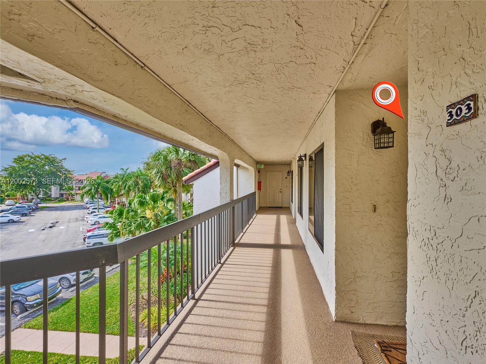 An outdoor apartment building walkway with a metal railing overlooking a parking lot — 10143 Mangrove Dr # 303, Boynton Beach FL 33437, BOYNTON BEACH, FL