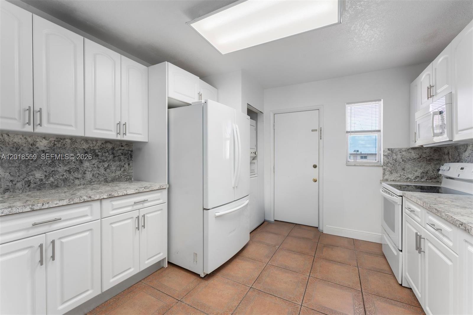 A kitchen features white cabinets, granite countertops, a white refrigerator, and brown tile flooring — 1950 W 54th St # 406, Hialeah FL 33012, HIALEAH, FL