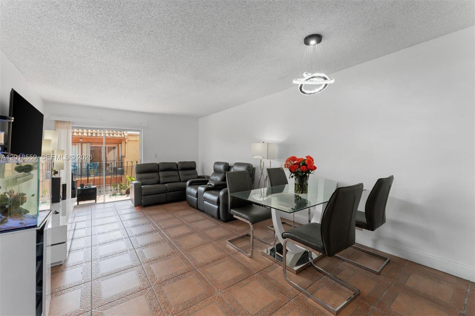 A living and dining area features tile flooring, a glass table, and a sliding glass door — 1950 W 54th St # 406, Hialeah FL 33012, HIALEAH, FL