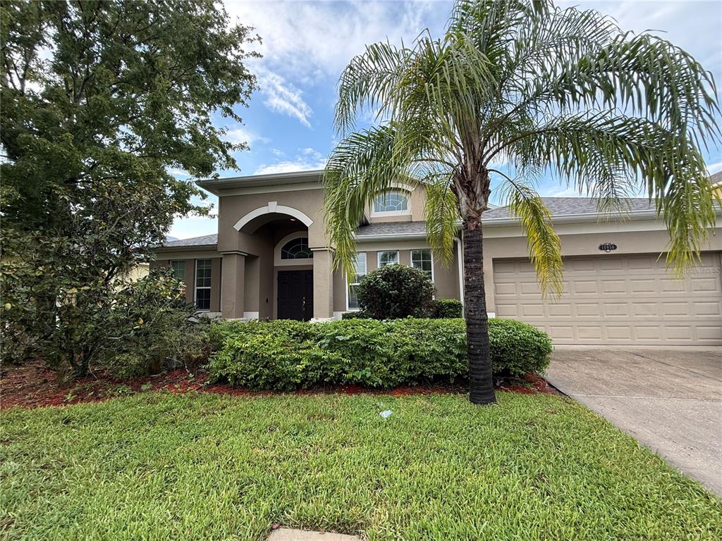 A single-story house with a beige exterior, a palm tree, and a two-car garage — 10856 BREAKING ROCKS DRIVE, TAMPA, FL