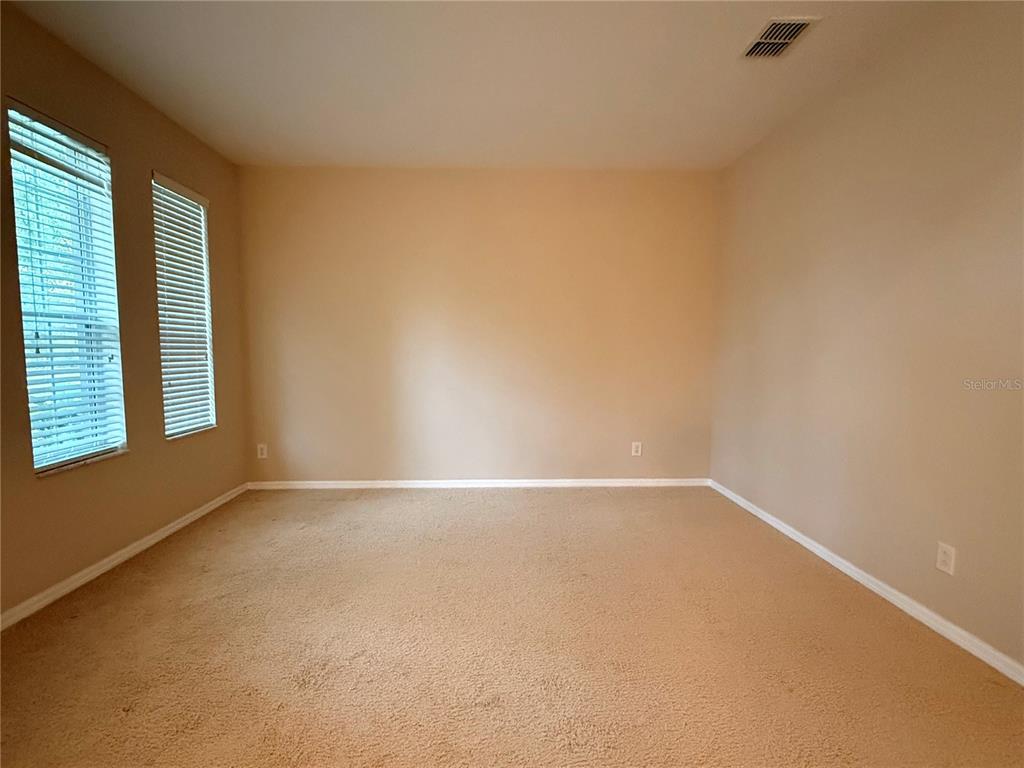 An empty room with beige carpet, tan walls, and two windows with white blinds — 10856 BREAKING ROCKS DRIVE, TAMPA, FL