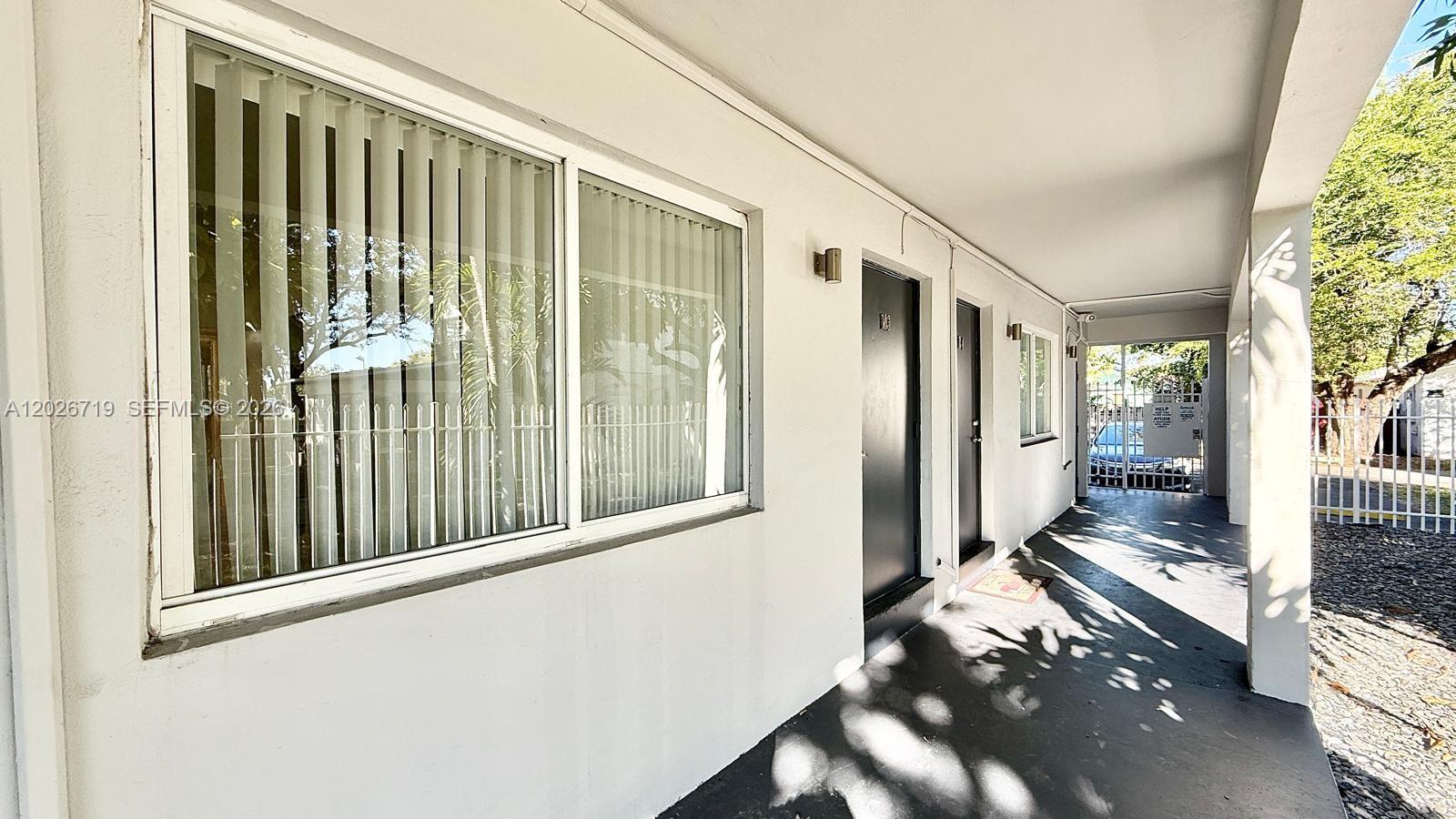 A covered exterior walkway leads past a large window and two dark entry doors — 42 SW 14th St # 103, Dania Beach FL 33004, DANIA BEACH, FL