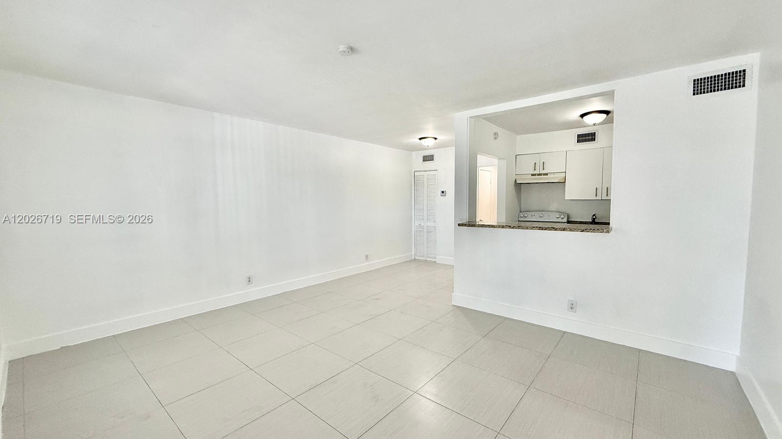 An open-concept living area features light-colored tile flooring and a pass-through kitchen window — 42 SW 14th St # 103, Dania Beach FL 33004, DANIA BEACH, FL