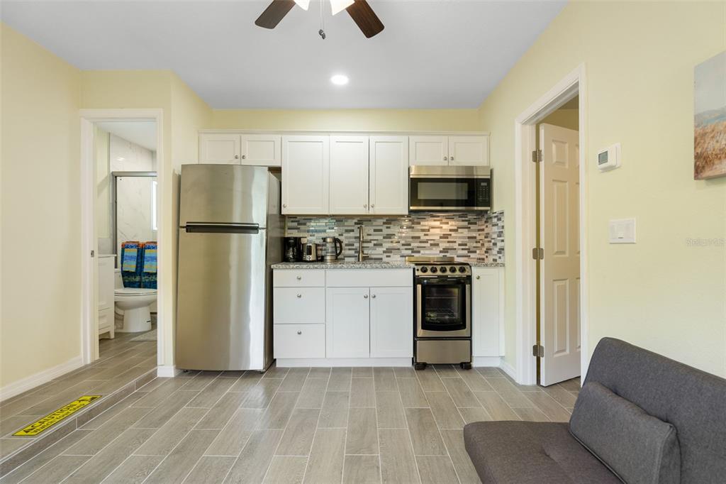 A small kitchen features white cabinets, stainless steel appliances, and gray tile flooring — 11953 DE LEON DRIVE, NORTH PORT, FL