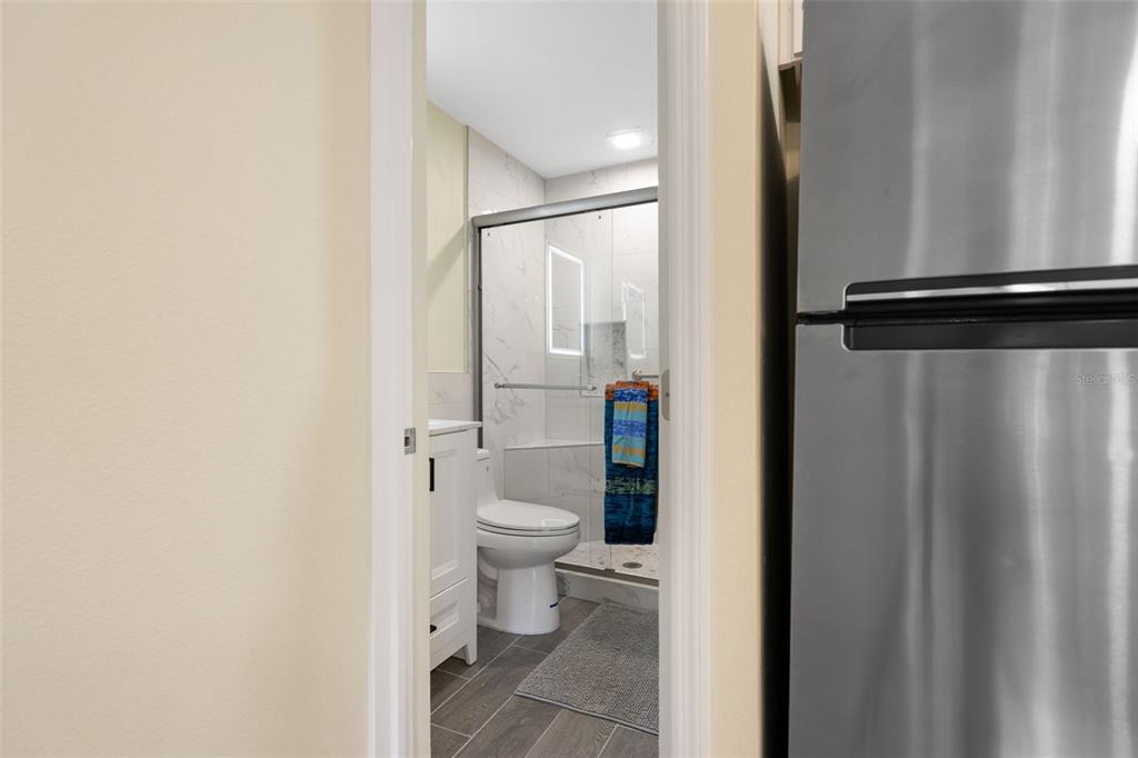 A view through a doorway shows a bathroom with a glass-enclosed shower and white vanity — 11953 DE LEON DRIVE, NORTH PORT, FL