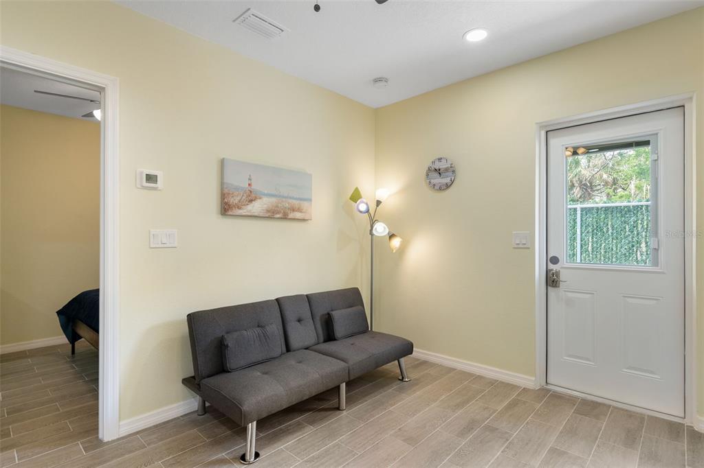 A room with light yellow walls, tile flooring, a gray futon, and a glass-paneled door — 11953 DE LEON DRIVE, NORTH PORT, FL