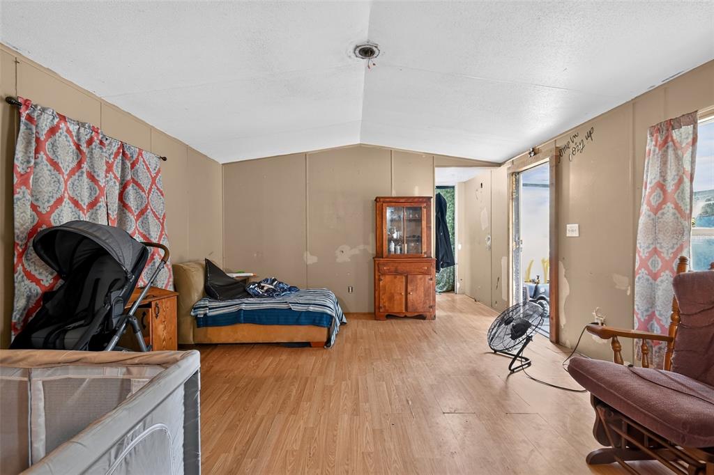 A sparsely furnished room with wood-look flooring, paneled walls, a bed, and a wooden hutch — 25005 BARTHOLOMEW STREET, CHRISTMAS, FL