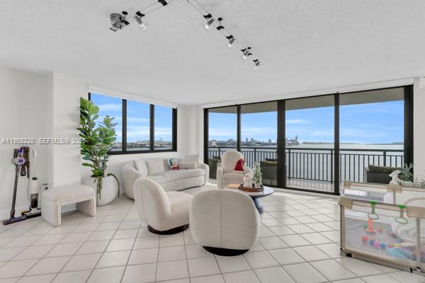 A living room with white tile floors, modern furniture, and large windows overlooking the water — 540 Brickell Key Dr # 832, Miami FL 33131, MIAMI, FL